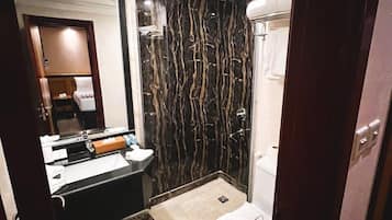 A bathroom with a black and white marble wall, a white toilet, a sink with a mirror, and a shower area.