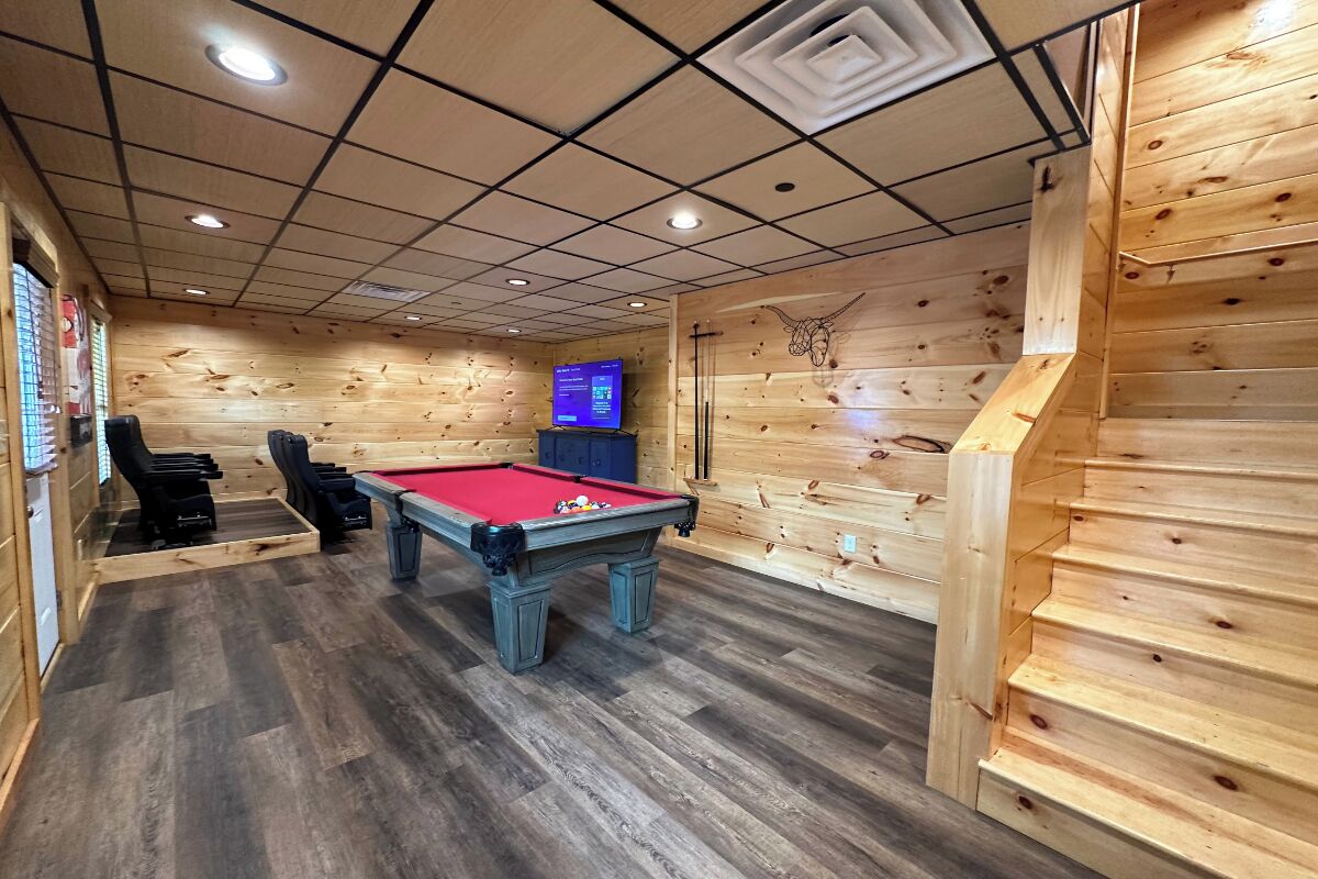 A pool table in a room with wooden walls and a grid ceiling.