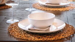 A dining table set with white bowls and plates, two wine glasses, and a woven placemat. - Gorgeous 4BD Lodge w/ POOL! Hot Tub + Theater (Sevierville)