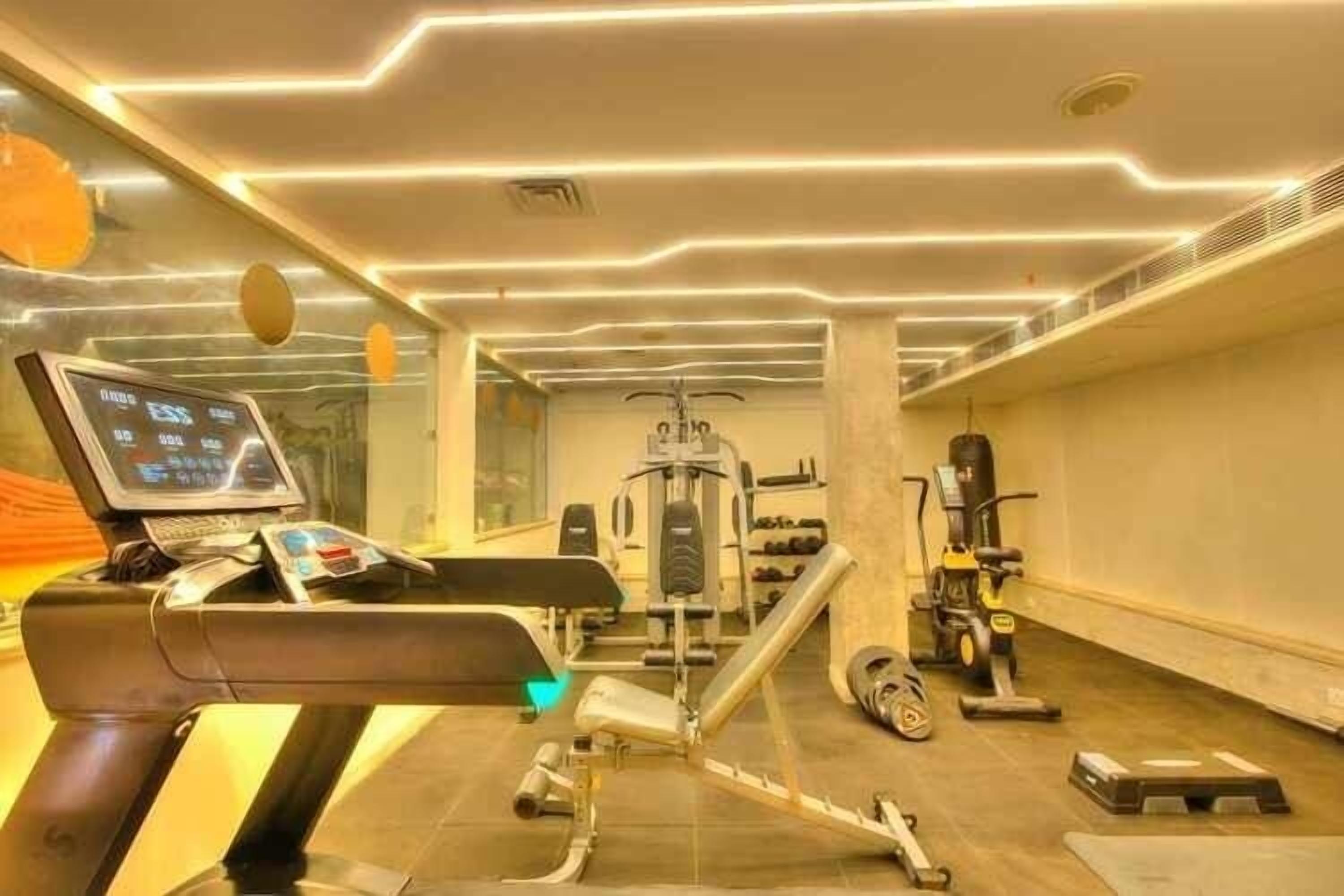 A modern gym with exercise equipment, a digital screen, and a treadmill.