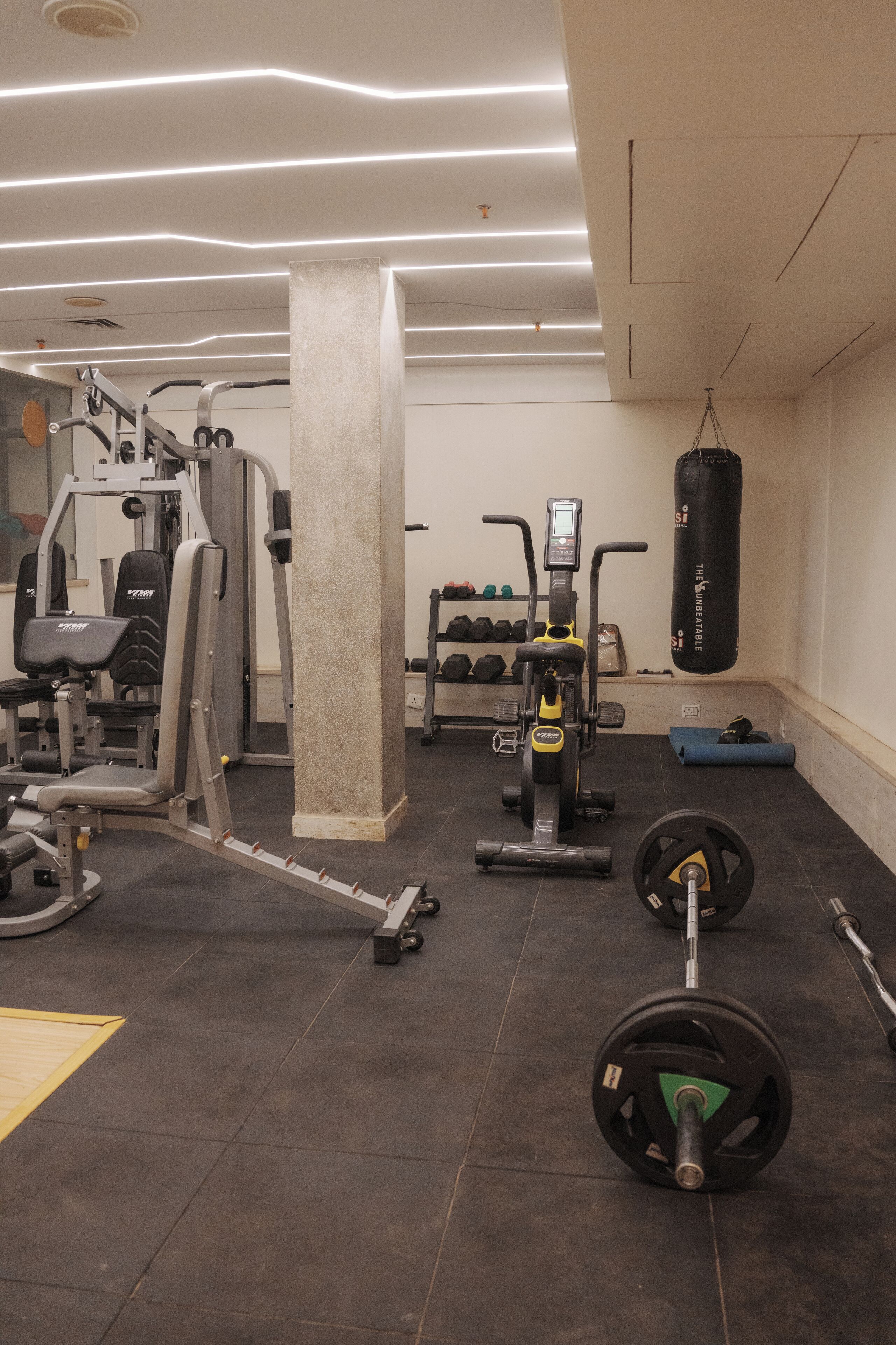 Een sportschool met trainingsapparatuur, een bokszak en gewichten.