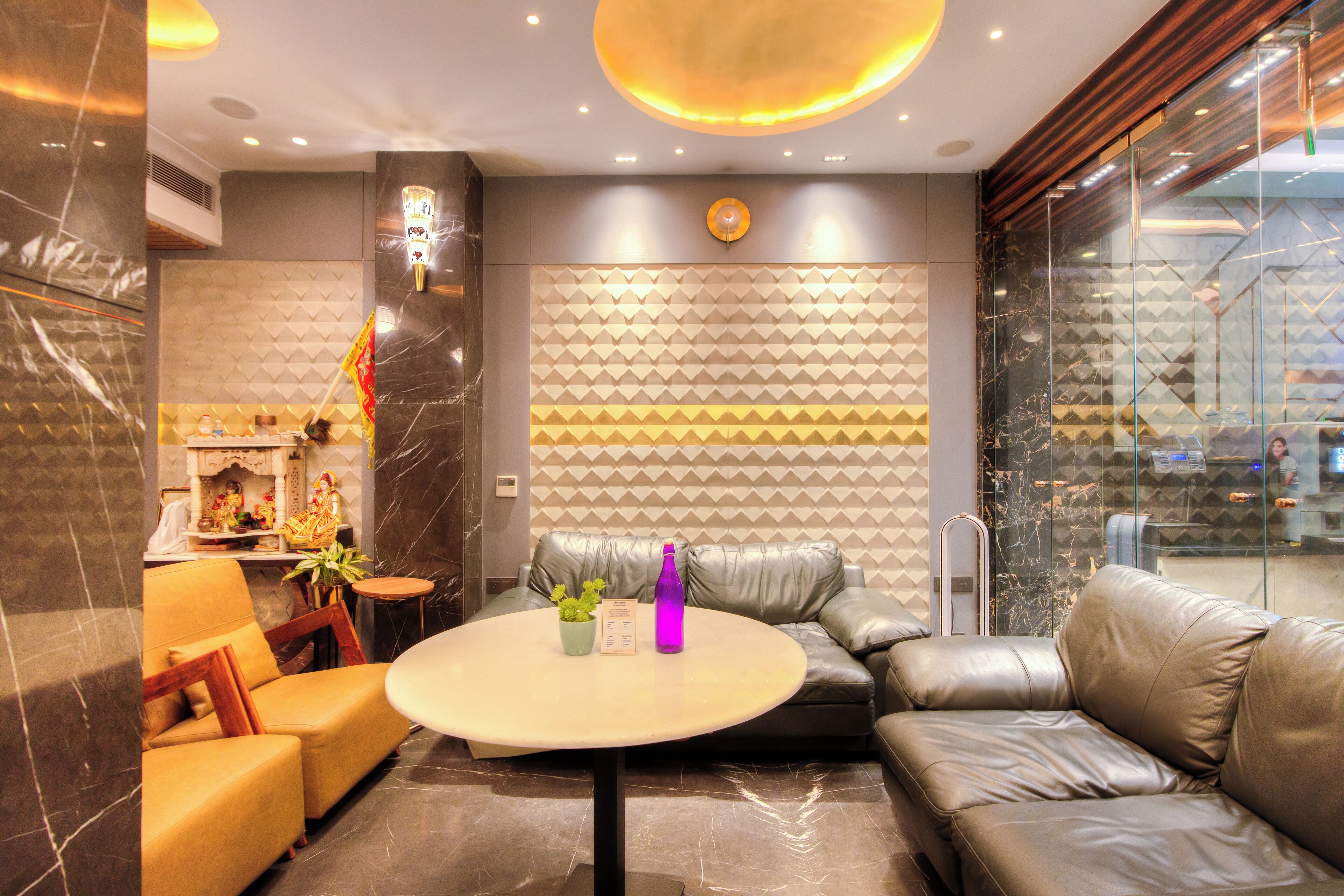 A modern lobby with a leather sofa, a round table, and a decorative wall with geometric patterns.