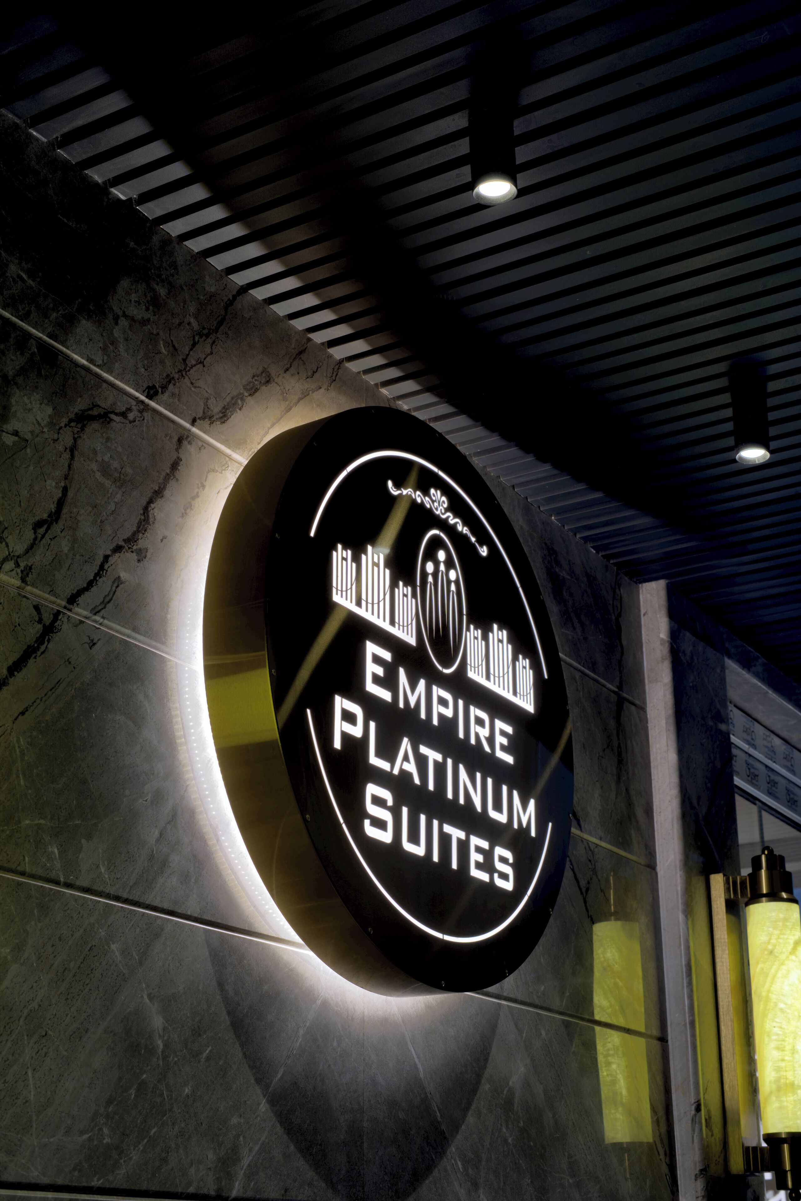 Ein rundes Schild mit dem Text "EMPIRE PLATINUM SUITES" vor dunklem Hintergrund.