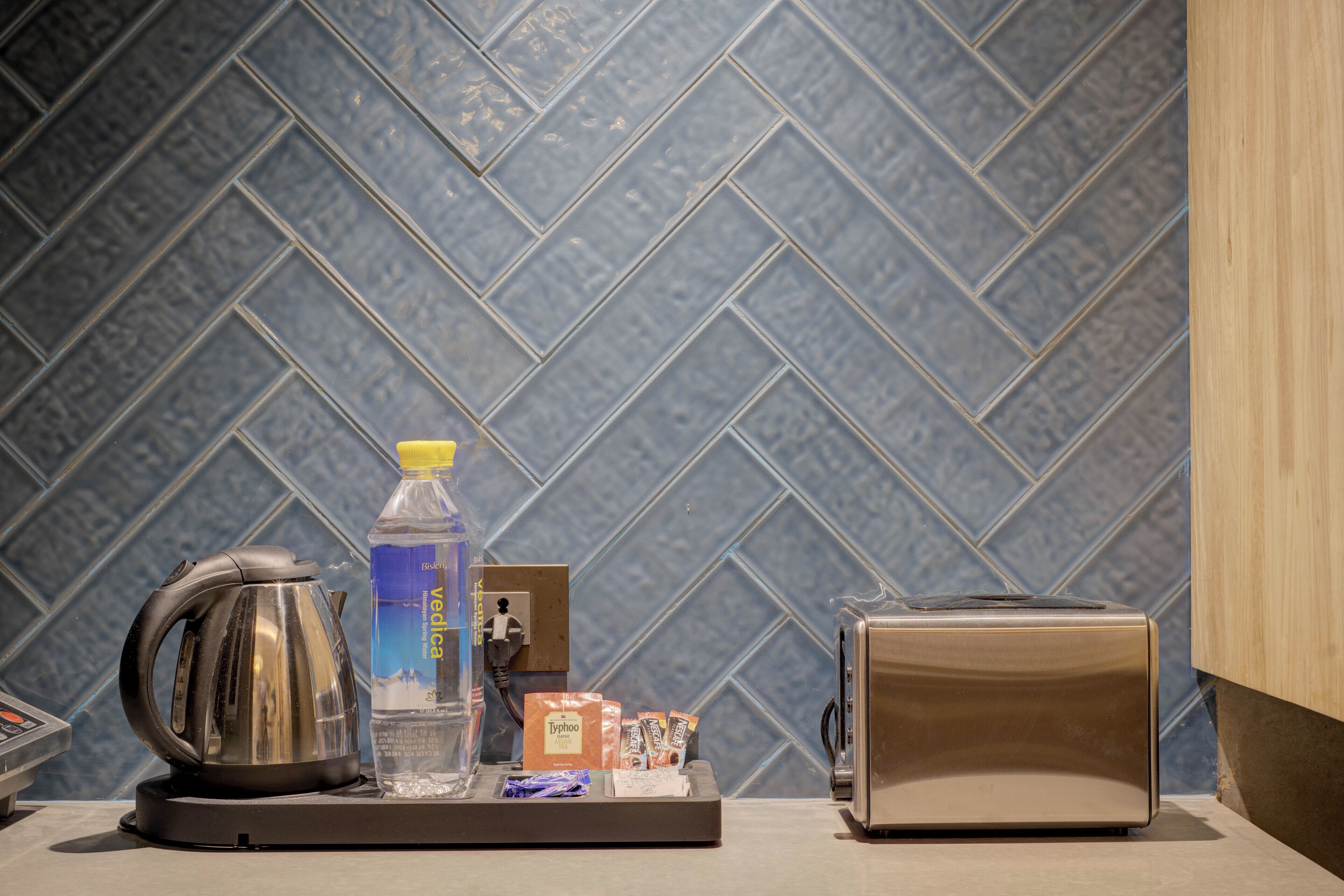 A kitchen counter with a kettle, a bottle of water, a toaster, and a small box of tea bags.