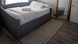 A bedroom with a bed, a ceiling fan, a mirror, and a door.