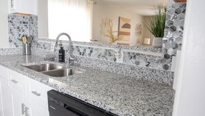 A modern kitchen with granite countertops, stainless steel sinks, and white cabinetry.
