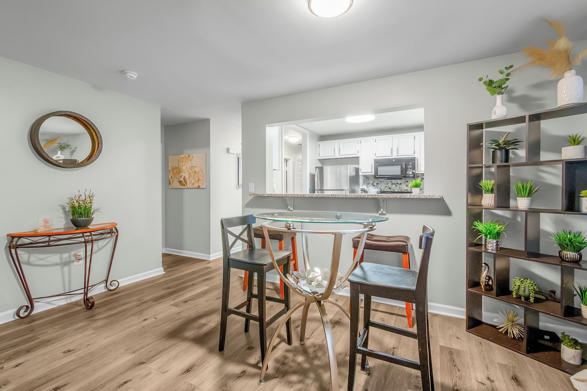 A modern kitchen with a central island, a dining area with mismatched chairs, and a living space with a bookshelf.