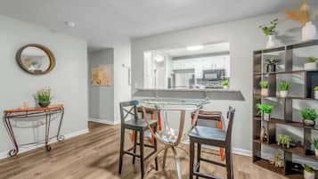 A modern kitchen with a central island, a dining area with mismatched chairs, and a living space with a bookshelf.
