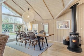 Un espace repas comprenant une table, des chaises et un poêle à bois.