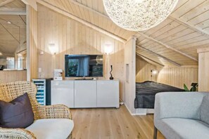 Un intérieur en bois avec un canapé, un téléviseur et un luminaire fixé au plafond.