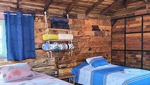 A rustic wooden room with two beds, a wooden ceiling, and a window with curtains. - Hotel Areca (Murillo)