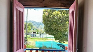 A wooden staircase leading to a balcony with a view of a green landscape and a tree. - Hotel Areca (Murillo)