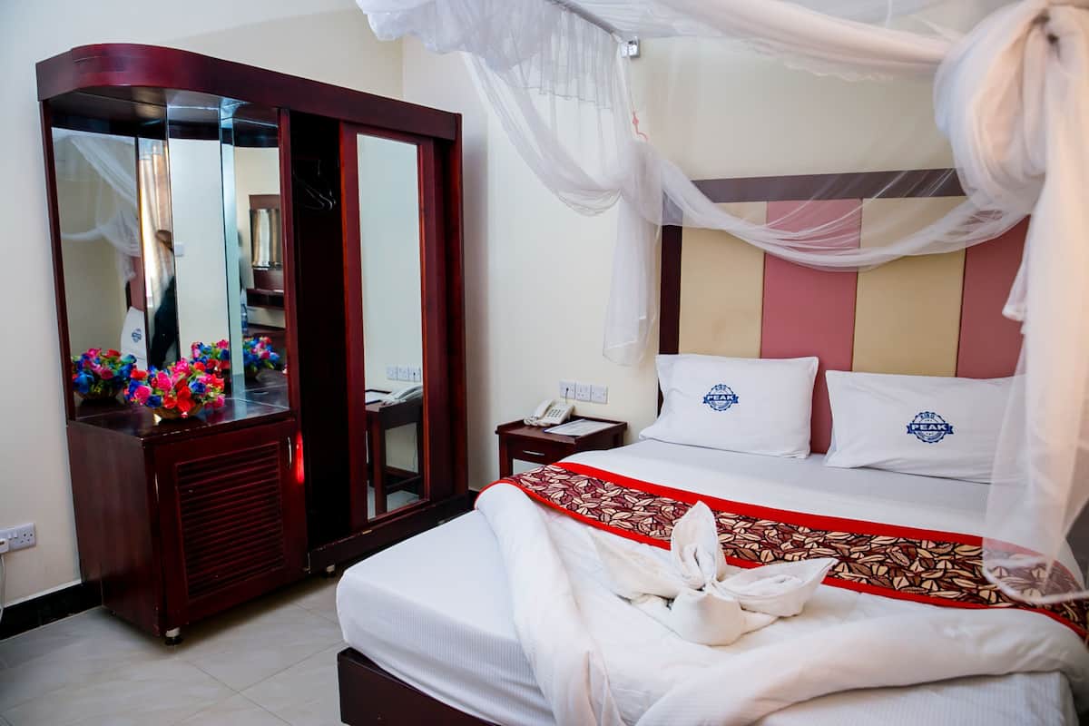 A hotel room with a bed, a wardrobe, a bedside table, and a mirror.