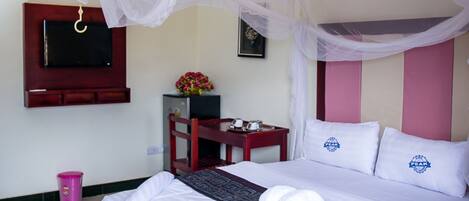 A hotel room with a bed, a TV mounted on the wall, a small table with a vase of flowers, and a chair.