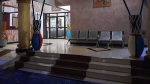 A lobby with a staircase, a reception desk, and a waiting area with chairs. - KIBO PEAK PALACE HOTEL (Morogoro)