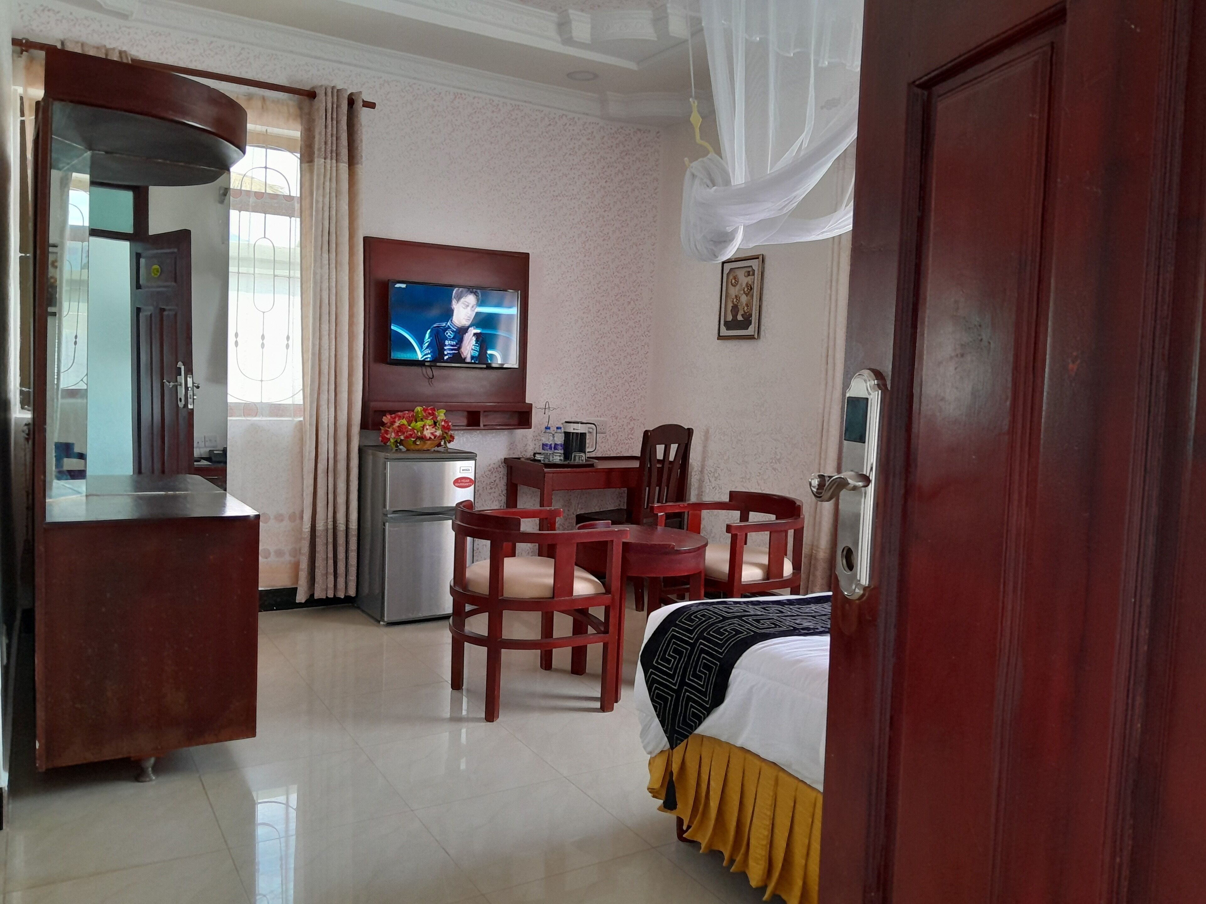 A hotel room with a bed, a desk, a chair, a television, and a refrigerator.