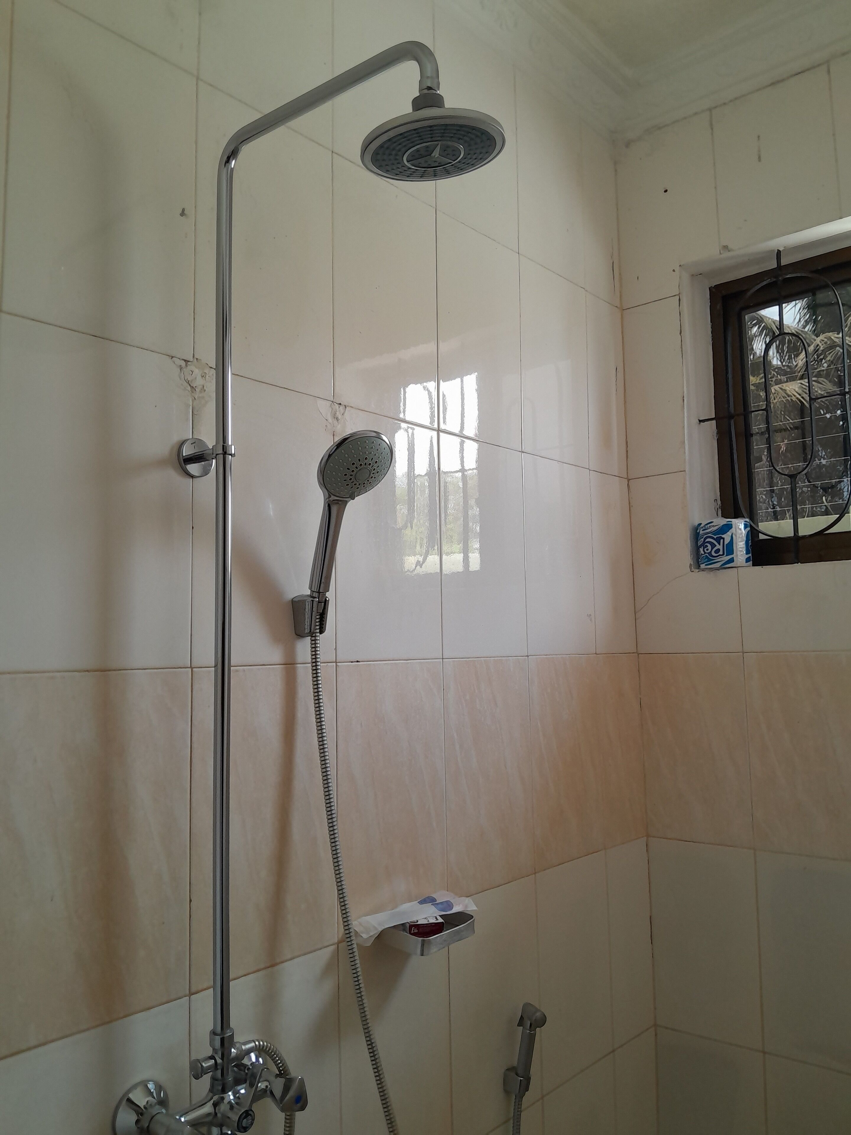 A shower with a handheld showerhead, a wall-mounted faucet, and a handheld showerhead with a hose.