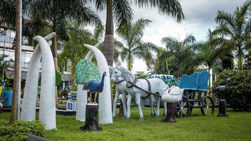 Un jardín de esculturas con pavos reales, caballos y un carruaje.