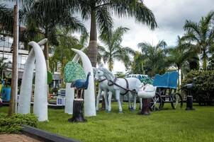 Un jardín de esculturas con pavos reales, caballos y un carruaje.