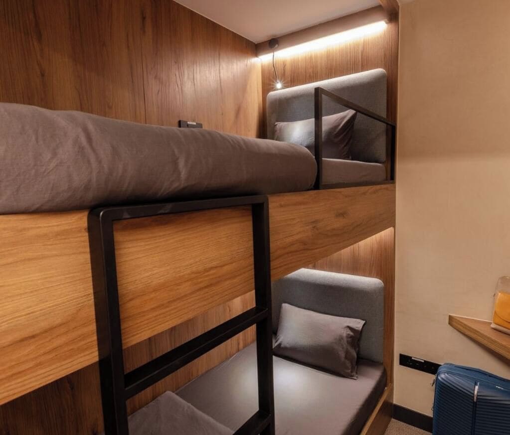 A bunk bed with a wooden frame and grey bedding.