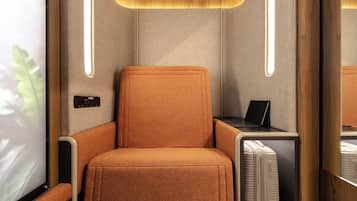 Et moderne interiør med en orange polstret lænestol, et lille bord med en bærbar computer og en indbygget aircondition.