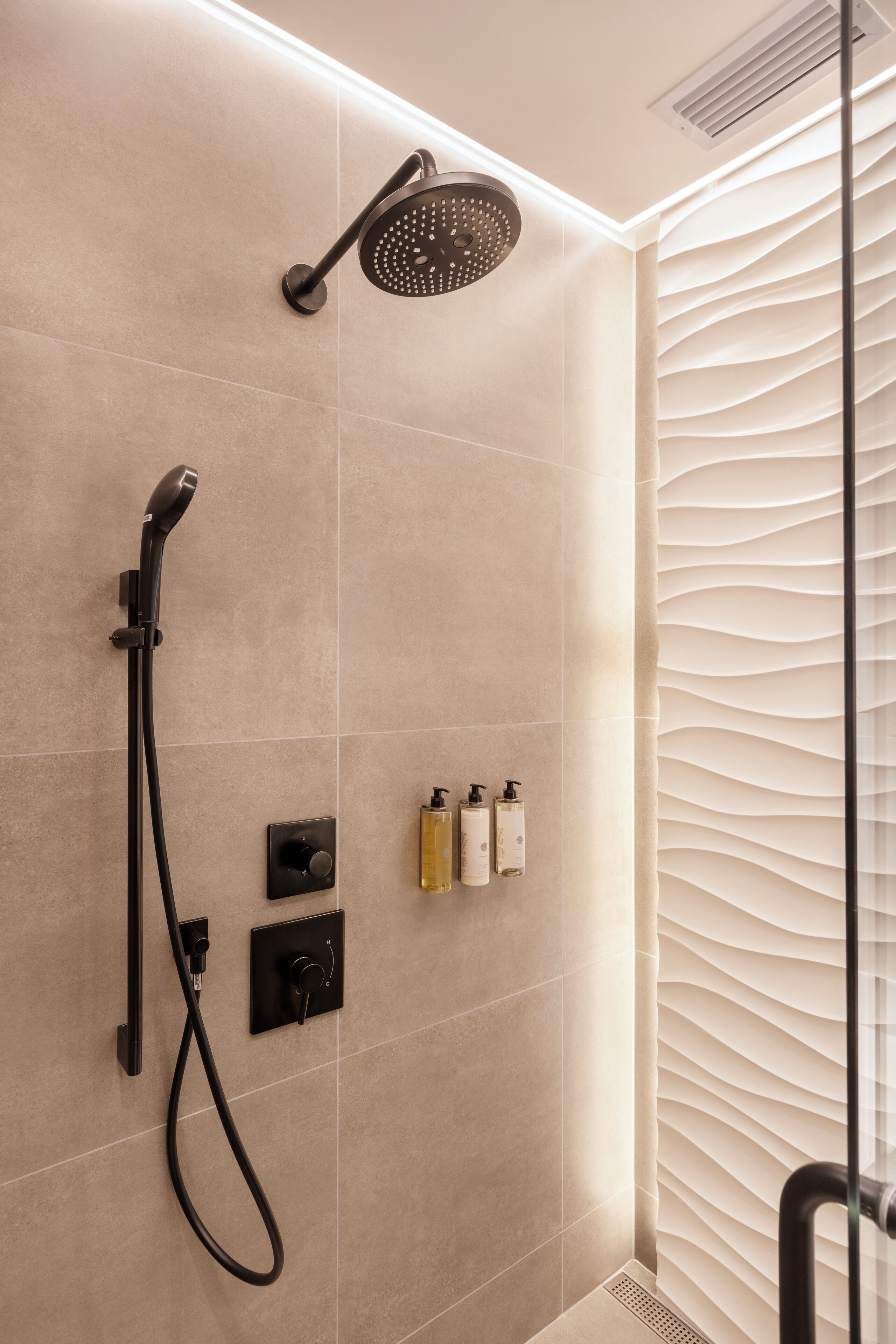 A modern shower with a handheld showerhead and a fixed wall-mounted showerhead.