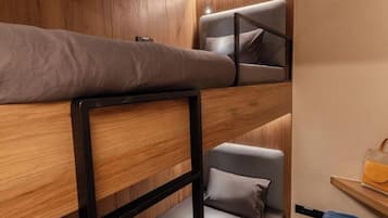 A bunk bed room with a wooden wall and a small table with a suitcase.
