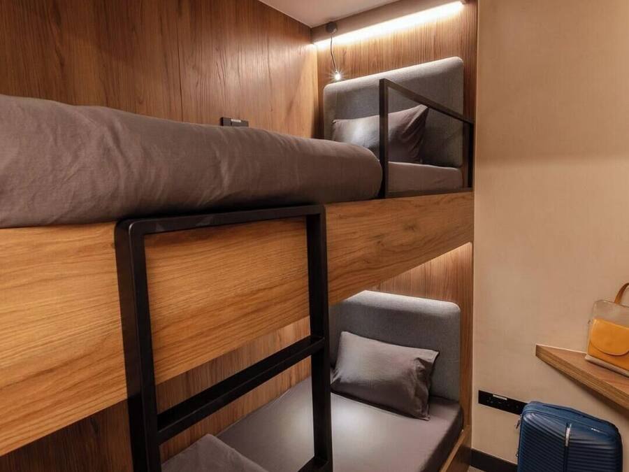 A bunk bed room with a wooden wall and a small table with a suitcase.