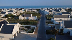 Un quartier résidentiel situé sur la côte, avec des maisons blanches, une rue principale et une vue sur la mer.