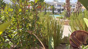 Un espace piscine entouré de verdure, avec un bâtiment en arrière-plan.