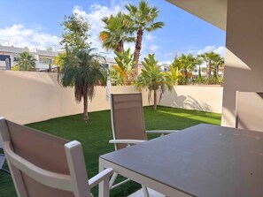 A patio with a table and chairs, surrounded by a well-maintained lawn and palm trees.
