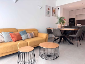 Una sala moderna con un sofá, dos mesas redondas y un comedor con sillas.