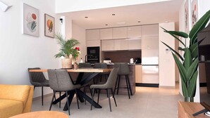 Une cuisine moderne avec un coin repas, comprenant un îlot central, des chaises et une plante en pot.