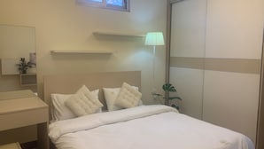 A bedroom with a bed, bedside table, lamp, and a window. - Holly Apartment - Truc Bach Lake (Hanoi)