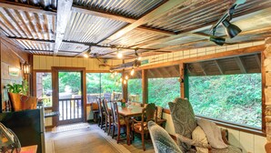 A cozy dining area with wooden tables and chairs, a large window with a view of greenery, and a ceiling with exposed beams and lights. - Dreamy Damascus Cabin ~ 1 Mi to Appalachian Trail (Damascus)