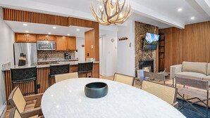 A modern kitchen with wooden accents, a dining area with a marble table, and a cozy seating arrangement.