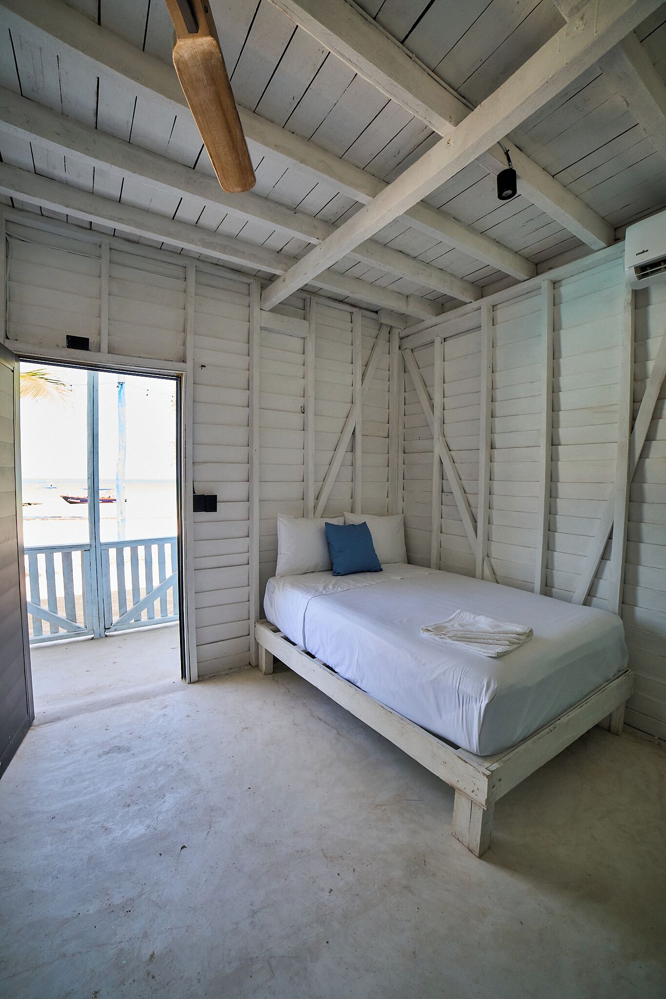 A room with a bed, a ceiling fan, and a door leading to an outdoor area.