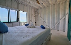 A bedroom with a large bed, a swan-shaped pillow, and a rolled towel.