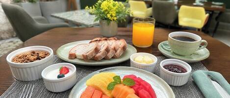 A breakfast setting with a plate of sliced fruit, a glass of orange juice, and a cup of coffee.