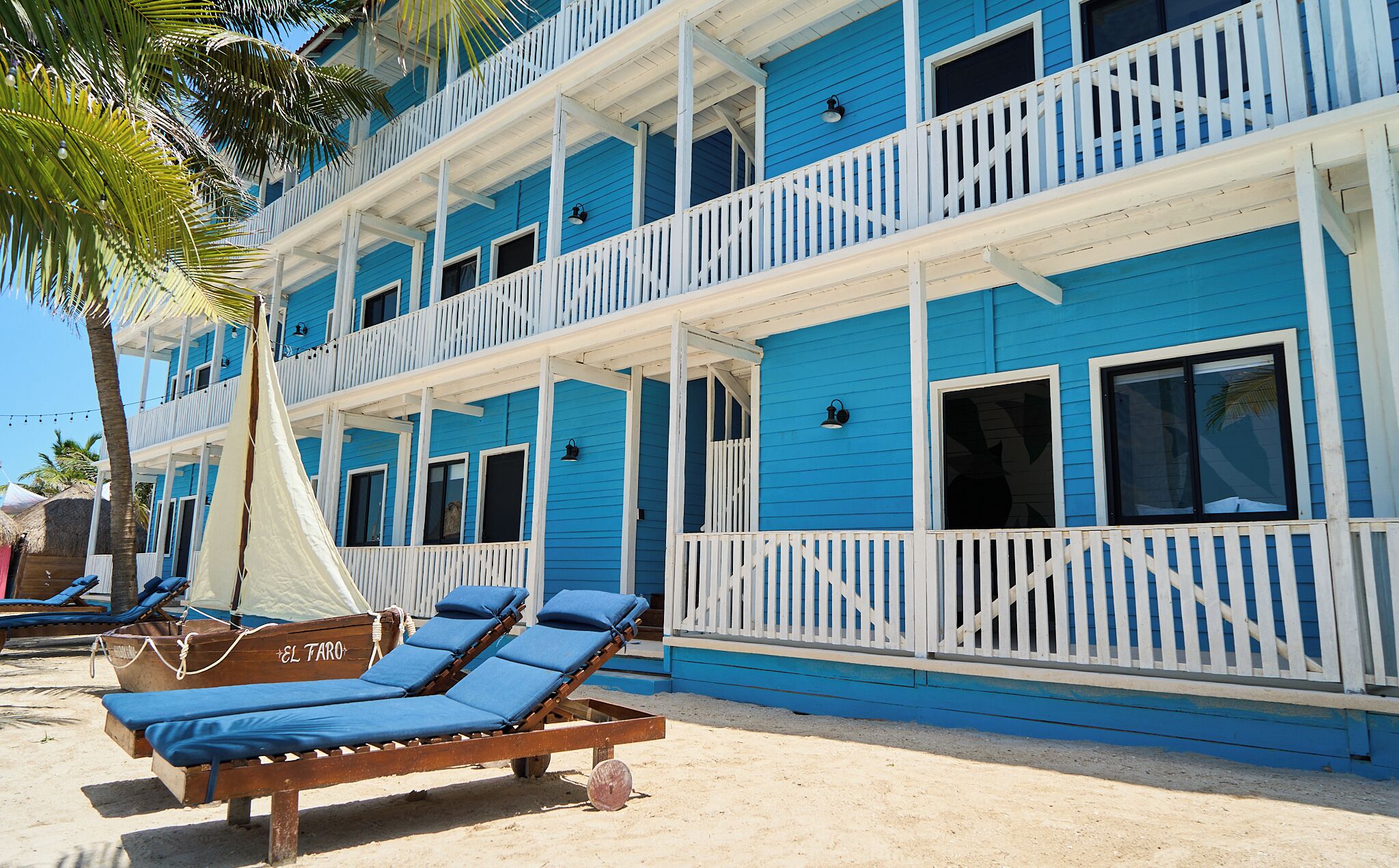 A beachfront hotel with multiple balconies, sun loungers, and a sandy beach area.