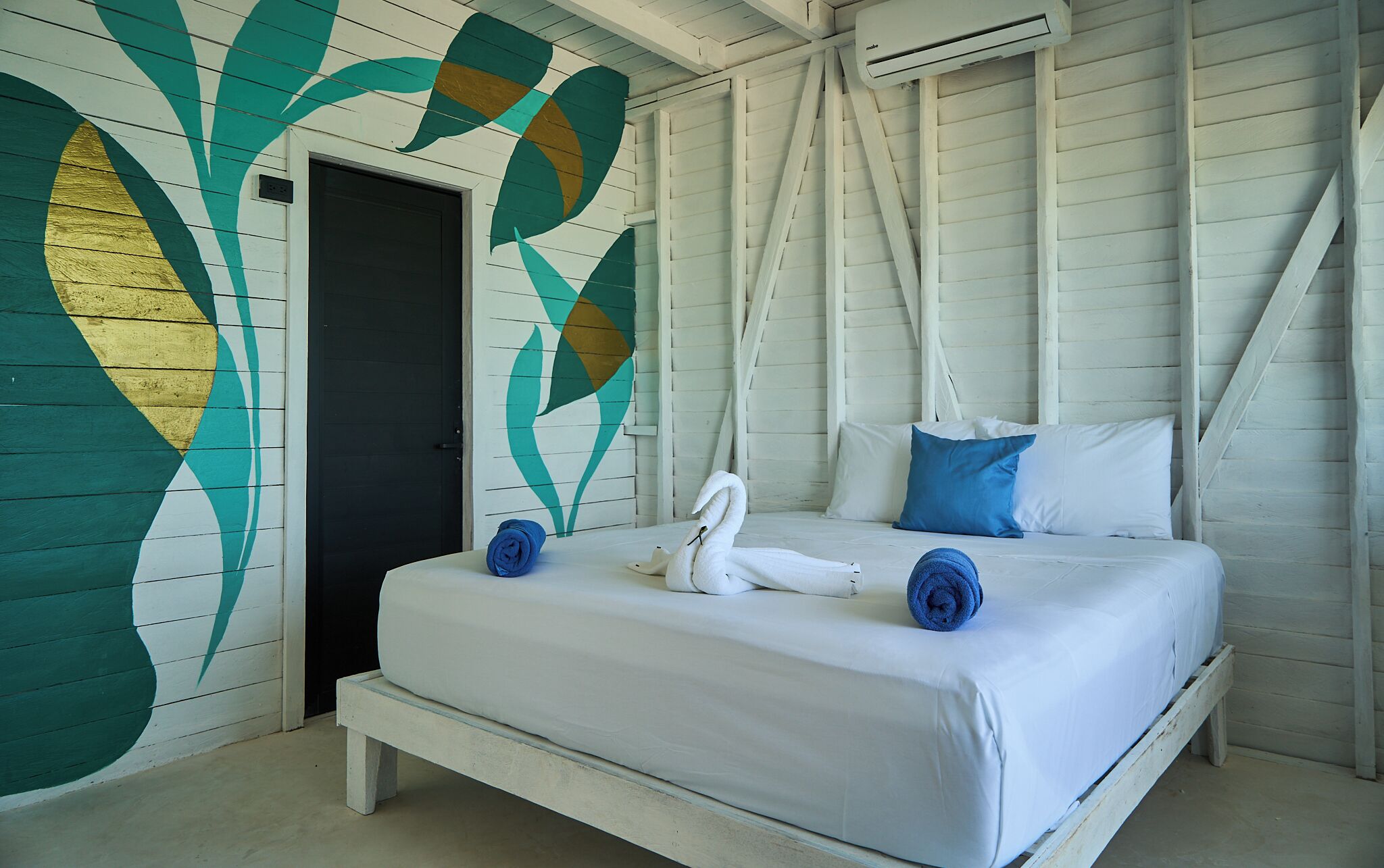 A room with a bed, a wall mural, and an air conditioning unit.
