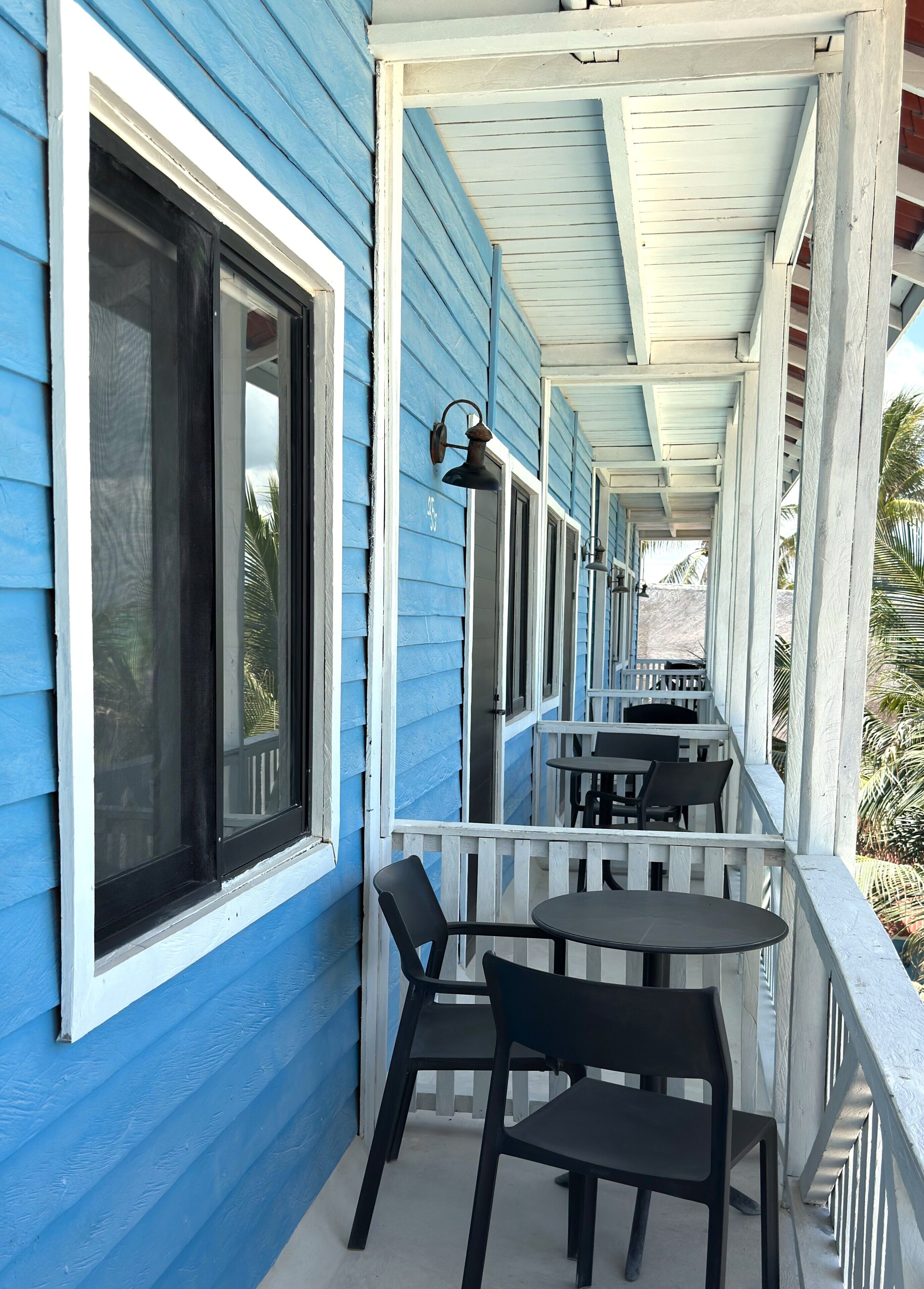 A covered porch with blue siding, white railings, and black outdoor furniture.