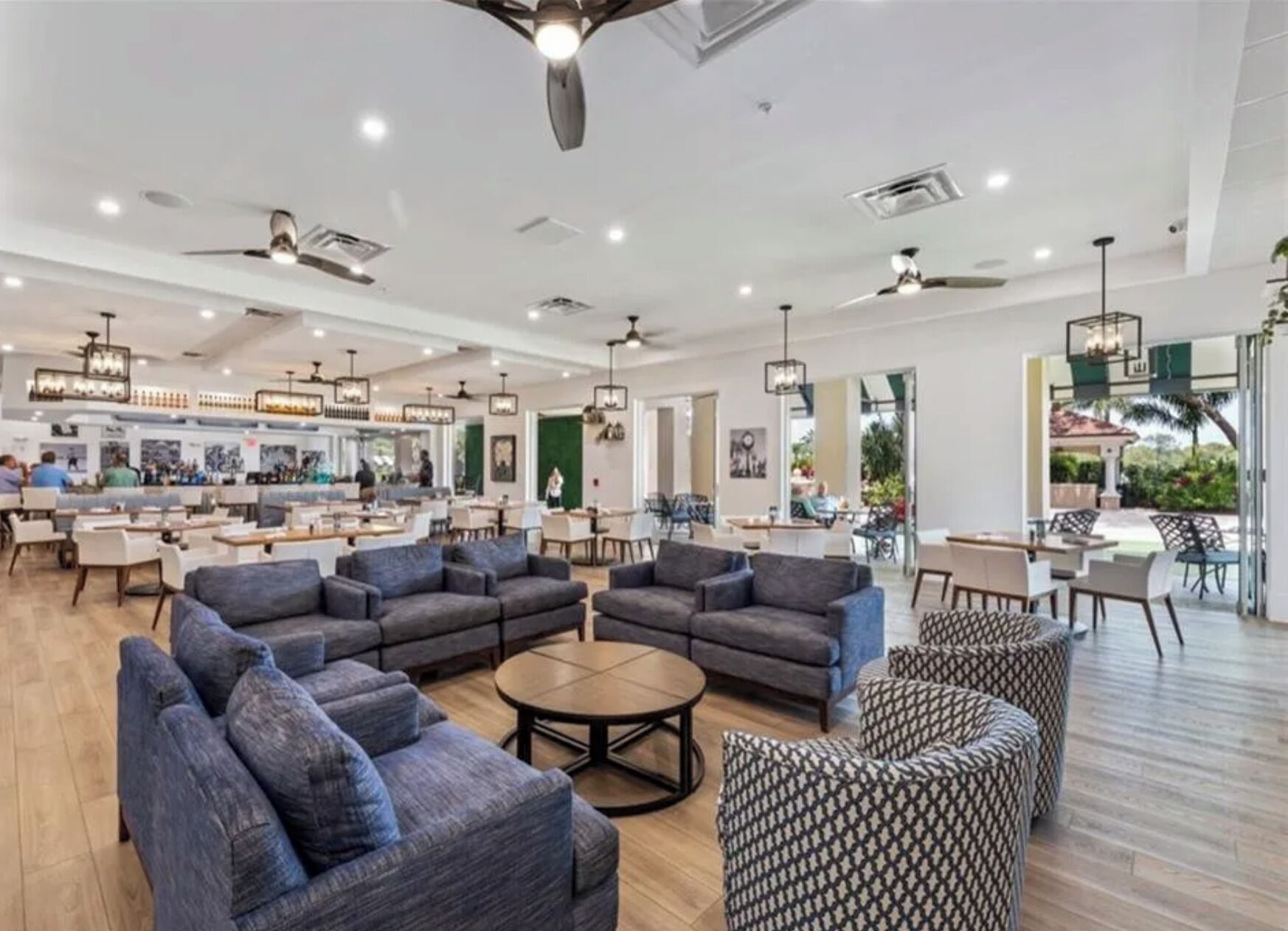 Ein großzügiger Innenbereich mit verschiedenen Sitzgelegenheiten, darunter Sofas und Sessel, und einer Bar im Hintergrund.