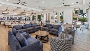Um espaço amplo e interno com diversas opções de assentos, incluindo sofás e cadeiras, e um bar ao fundo.