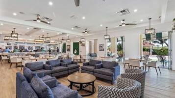 Ein großzügiger Innenbereich mit verschiedenen Sitzgelegenheiten, darunter Sofas und Sessel, und einer Bar im Hintergrund.