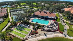 Vista aérea de um resort com uma piscina grande, quadras de tênis e um clube.