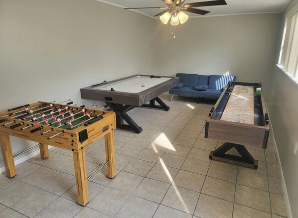 Una habitación con mesa de futbolín, mesa de billar y un sofá azul.