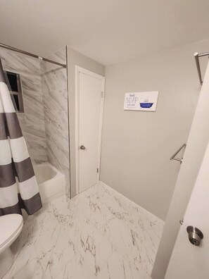 A bathroom with a shower, toilet, and a sign on the wall. - Central 3 Bedroom AC Home with Gameroom

 (Lakeland)