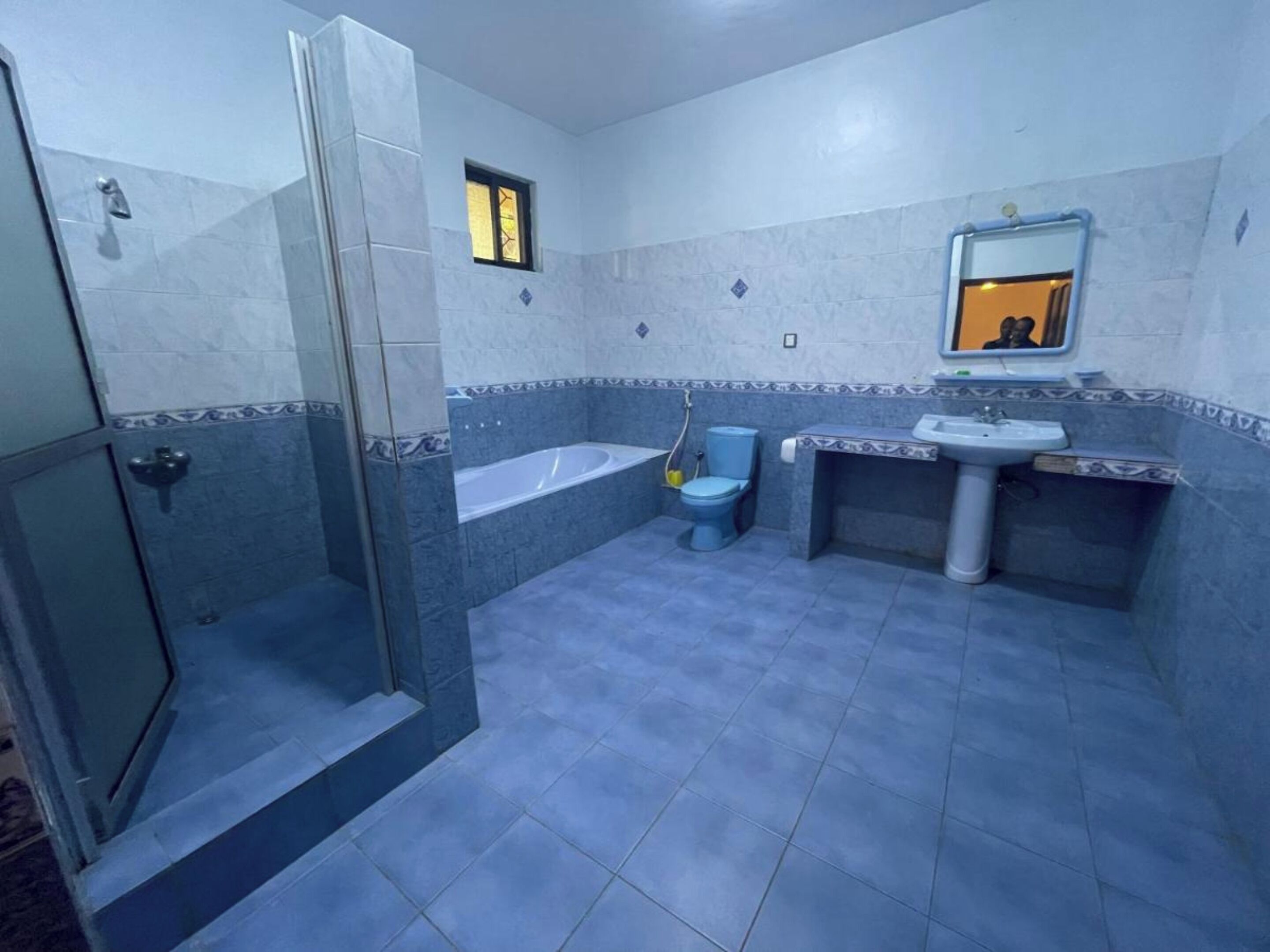A bathroom with a glass-enclosed shower, a bathtub, a toilet, and a sink.