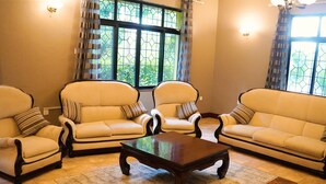 Een woonkamer met twee banken en twee fauteuils, een houten salontafel en een kamerbreed tapijt met een patroon.